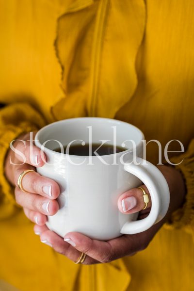 Vertical stock photo of a woman holding a coffee cup.