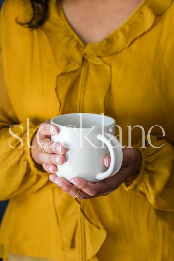 Vertical stock photo of a woman holding a coffee cup.