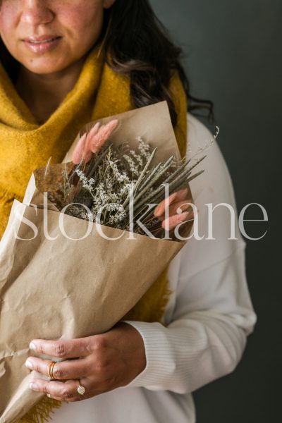 Vertical stock photo of a woman holding a dried fall bouquet.