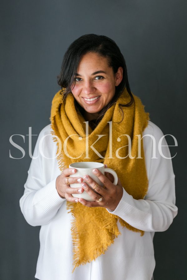 Vertical stock photo of a woman holding a cup of coffee.