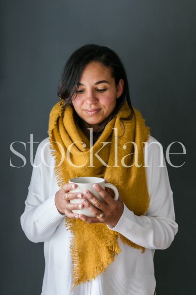 Vertical stock photo of a woman holding a cup of coffee.