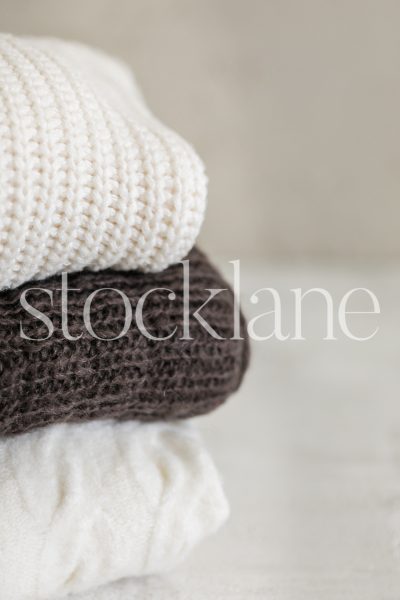 Vertical stock photo of neutral colored sweaters.