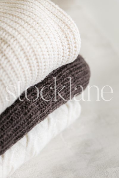 Vertical stock photo of neutral colored sweaters.