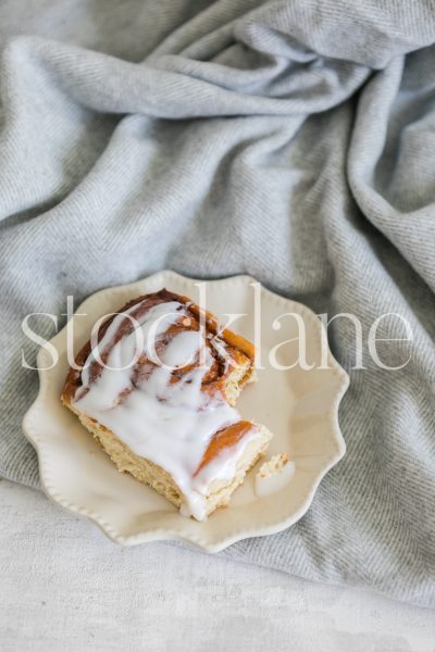 Vertical stock photo of a cinnamon roll on a gray blanket.