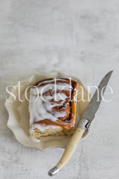 Vertical stock photo of a cinnamon roll on a vintage plate.