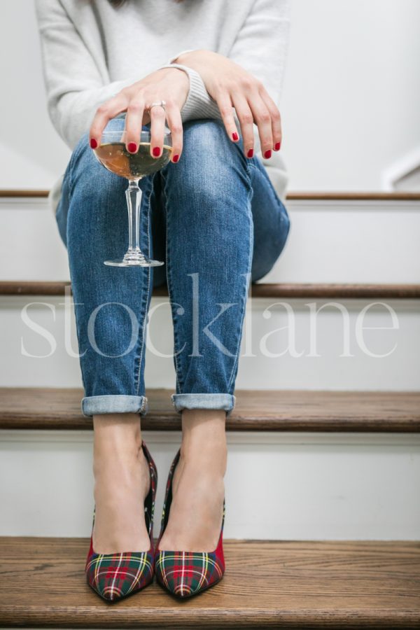 Vertical stock photo of woman sitting on steps with a glass of champagne