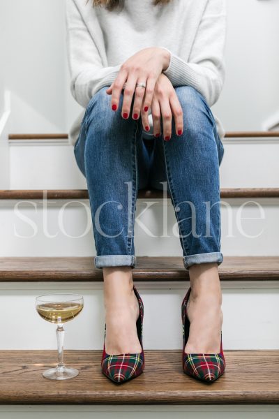 Vertical stock photo of woman sitting on steps with a glass of champagne