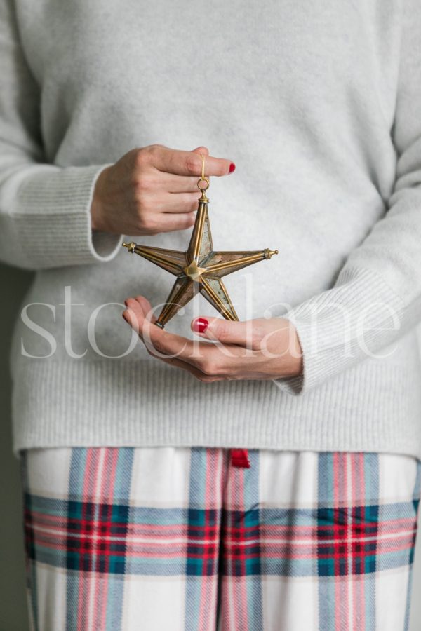 Vertical holiday stock photo of a woman holding a star ornament.