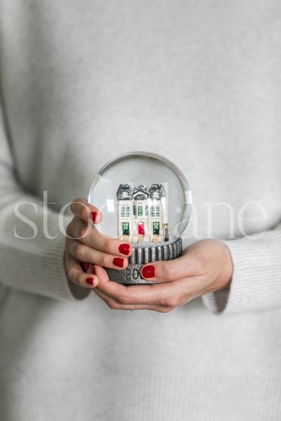 Vertical stock photo of a woman holding a holiday snow globe.