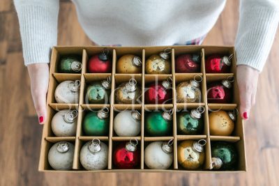 Horizontal stock photo of a woman holding a box of Christmas ornaments.