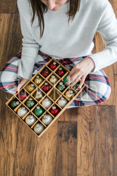 Vertical stock photo of a woman holding a box of Christmas ornaments.