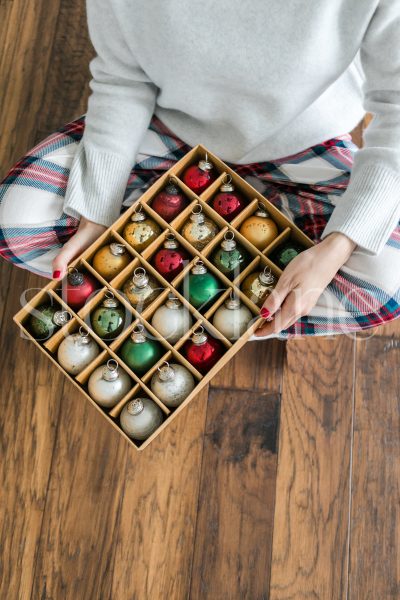 Vertical stock photo of a woman holding a box of Christmas ornaments.