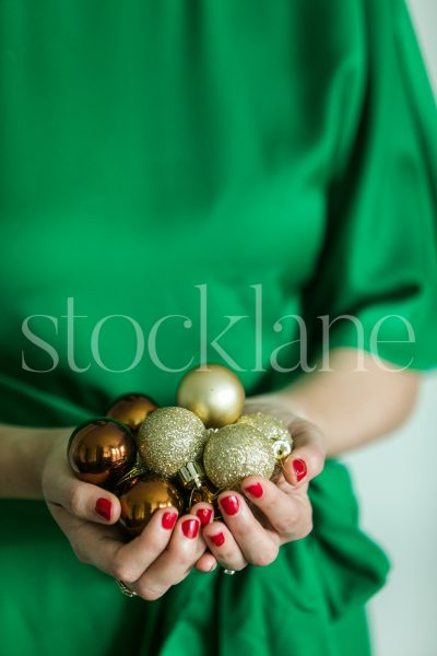 Vertical stock photo of woman holding gold ornaments