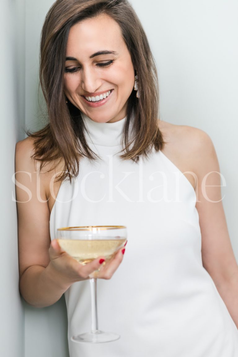 Vertical Stock photo of a woman in a white dress with a glass of champagne