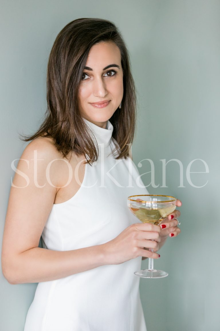 Vertical Stock photo of a women in a white dress with a glass of champagne