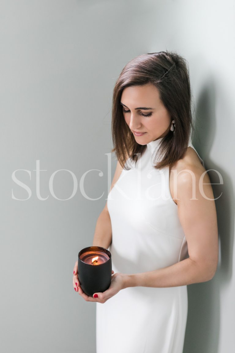 Vertical stock photo of a woman in a white dress with a candle