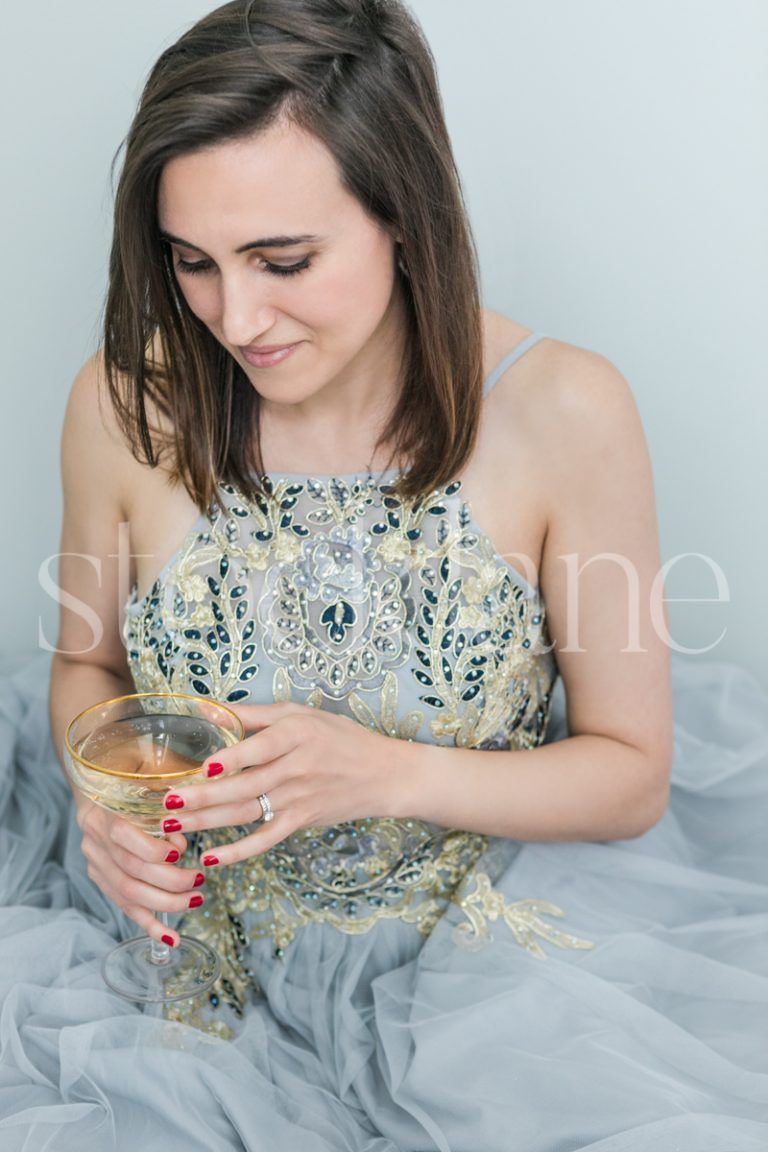 Vertical stock photo of a woman in a light blue dress with a glass of Champagne