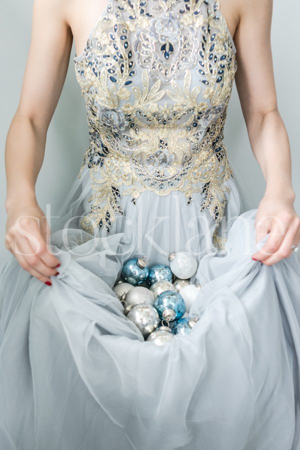 Vertical stock photo of a woman in a light blue dress with Christmas ornaments