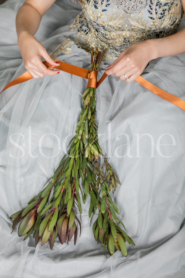 Vertical stock photo of a woman in a light blue dress with Christmas greenery