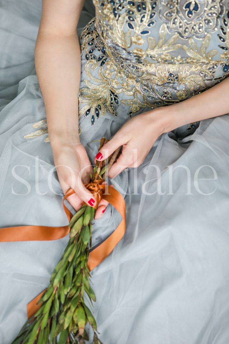 Vertical stock photo of a woman in a light blue dress with Christmas greenery