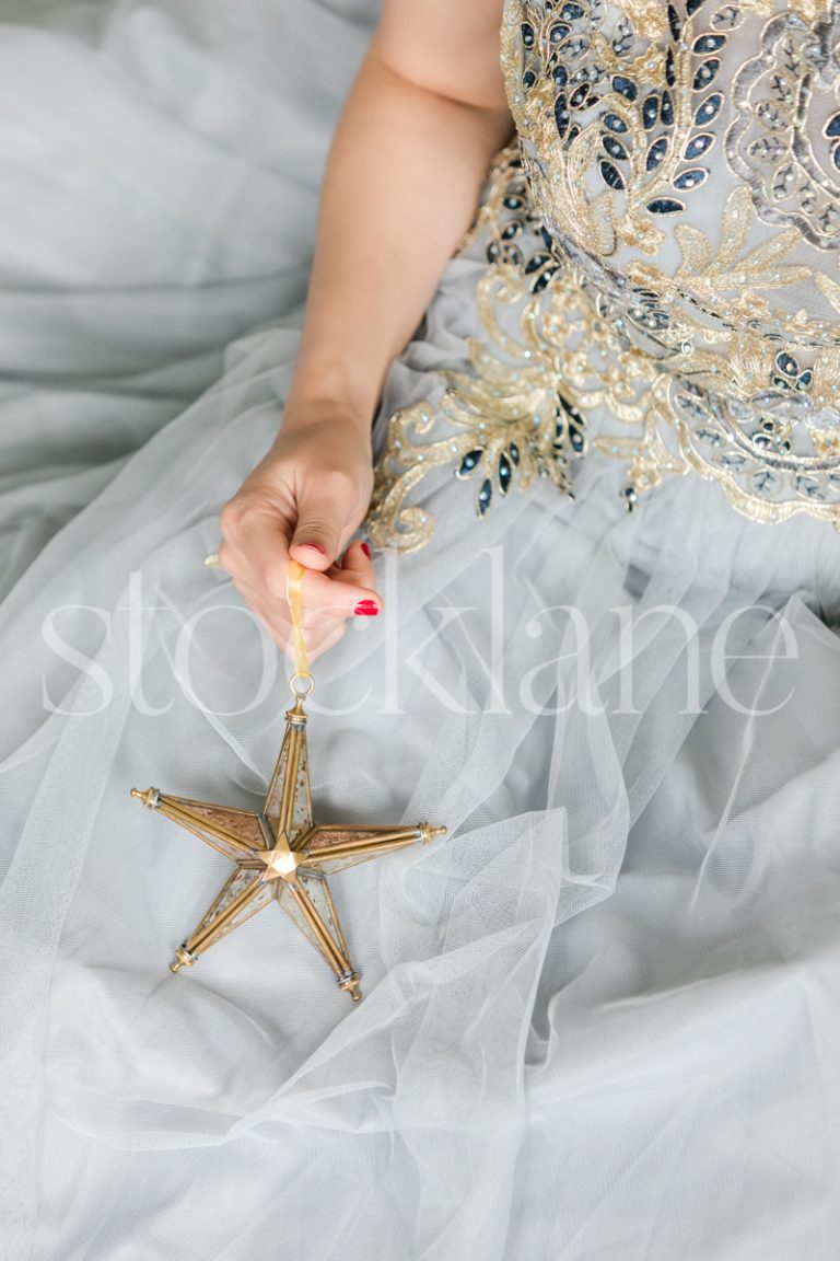 Vertical Stock photo of a woman in a white dress with a Christmas ornament