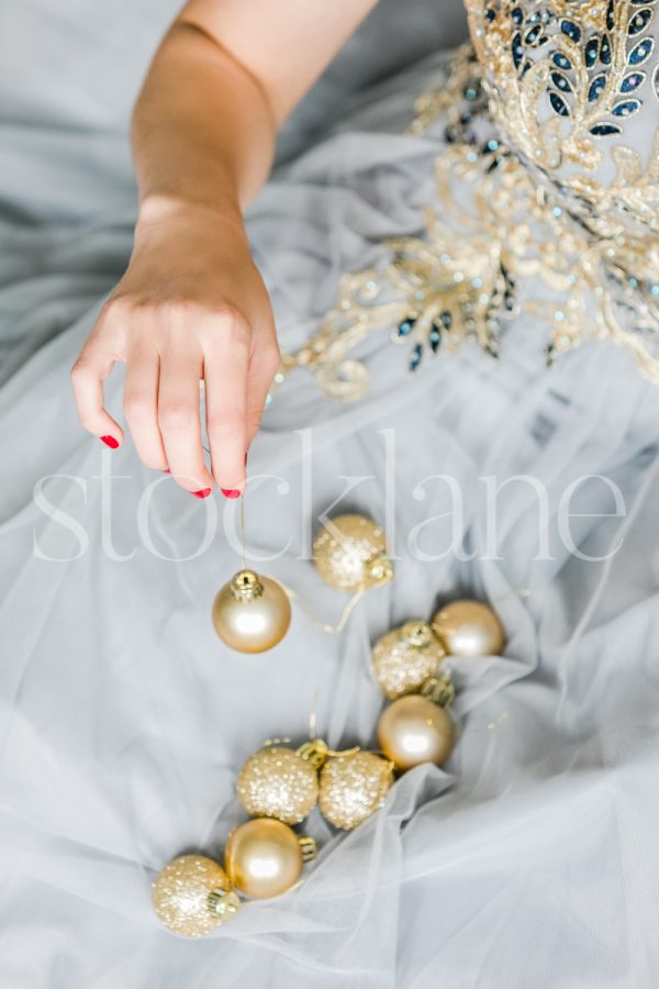 Vertical stock photo of a woman in a light blue dress with Christmas ornaments