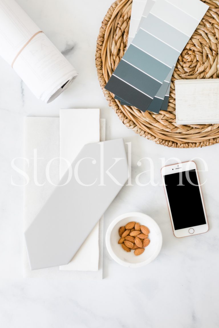 Vertical stock photo of a desktop with tile samples, color swatches and an iPhone