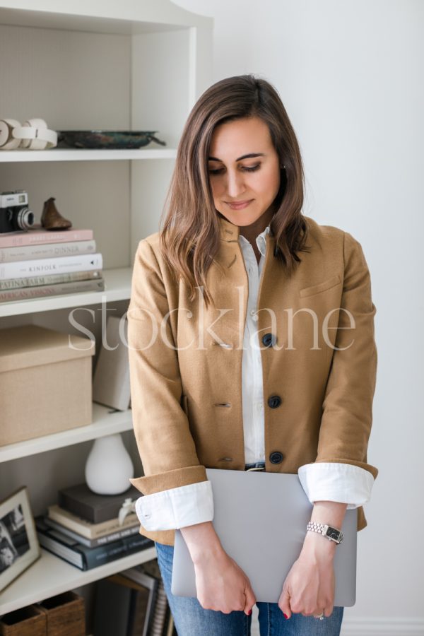 Vertical stock photo of a woman holding a laptop computer.