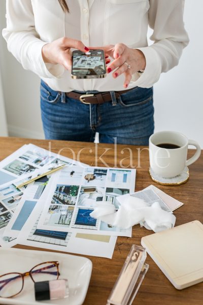 Vertical stock photo of a woman taking a photo with her phone.