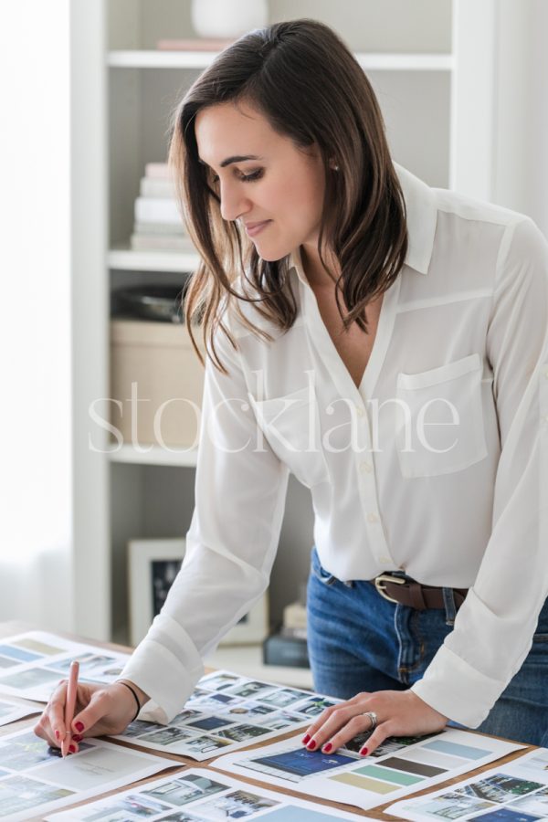 Vertical stock photo of a woman working on a mood board at her desk.