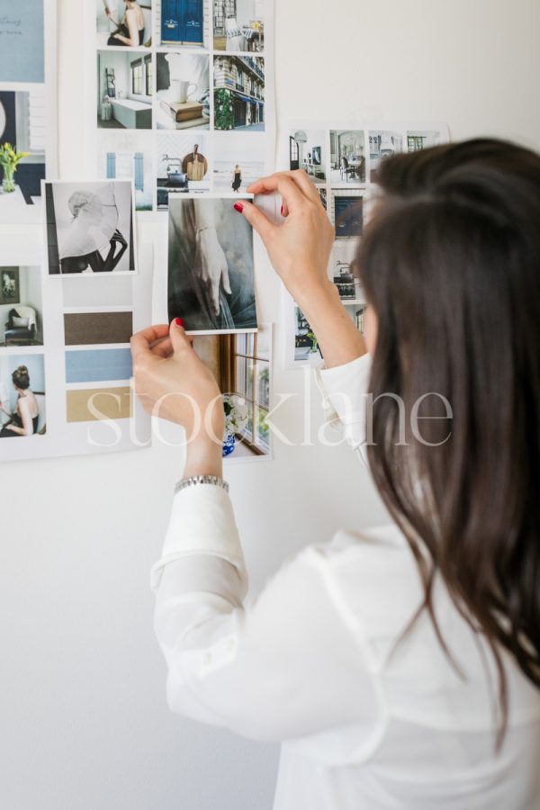 Vertical stock photo of a woman putting together a mood board.