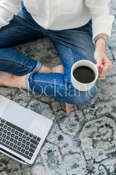 Vertical stock photo of a woman having a coffee while working at her computer.