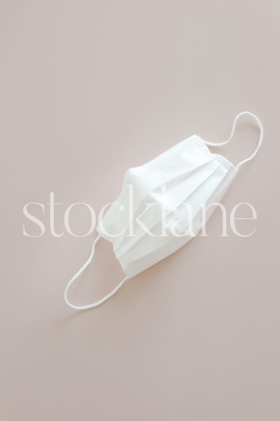 Vertical stock photo of a mask on a pink background