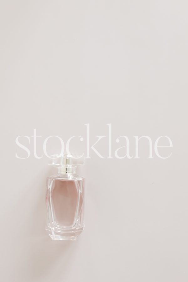 Vertical stock photo of a pink perfume bottle