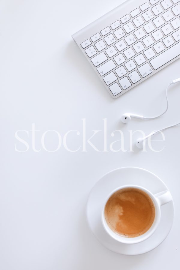 Vertical stock photo of a desktop with a keyboard, headphones and a coffee cup