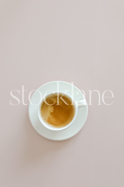 Vertical stock photo of a cup of coffee on a pink background