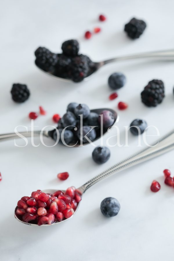 Vertical stock photo of three spoons with berries