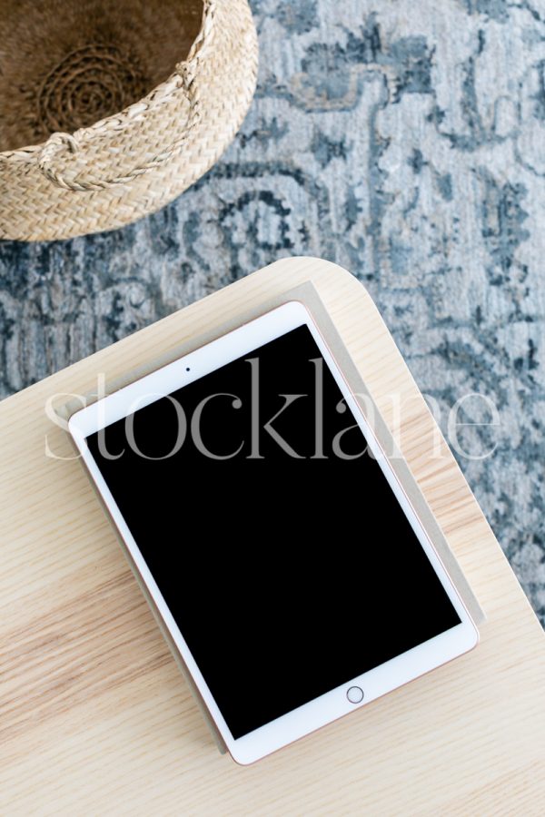 Vertical stock photo of an iPad on a neutral color table.