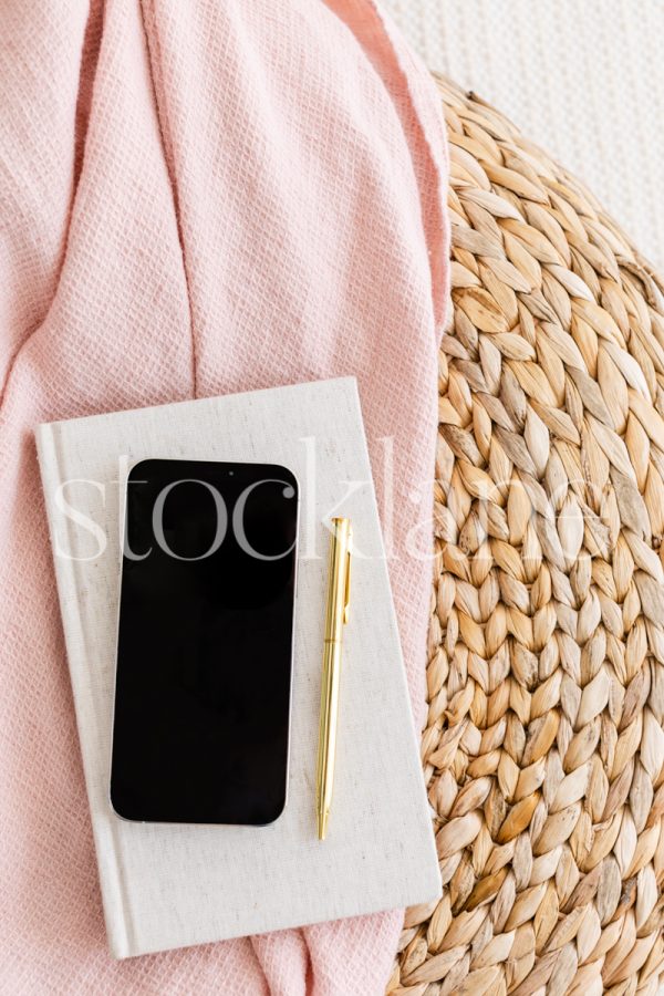 Vertical stock photo of a phone mockup in pink and neutral colors.