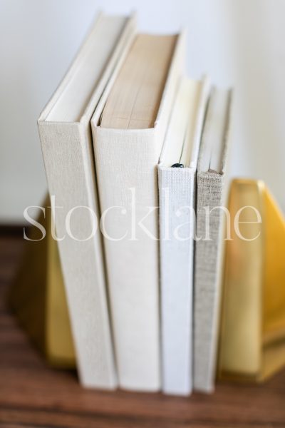 Vertical stock photo of a stack of books in neutral colors.