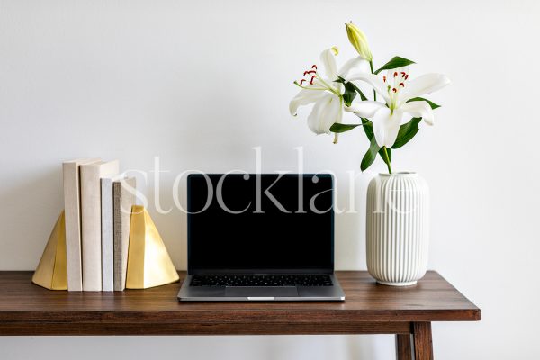 Horizontal stock photo with white asian lilies, books, and a computer