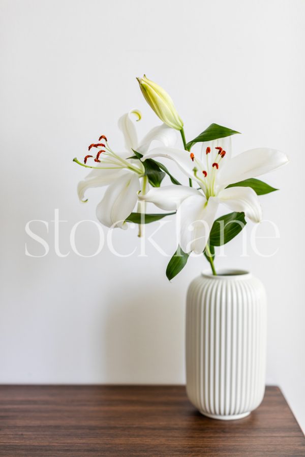 Vertical stock photo of a vase with white Asian lilies