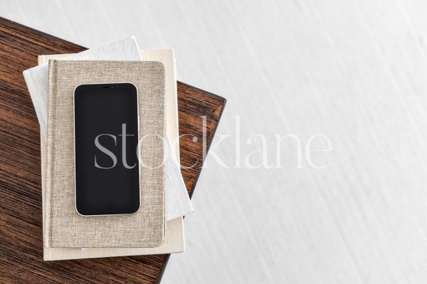 Horizontal stock photo of a phone on a stack of neutral colored books.