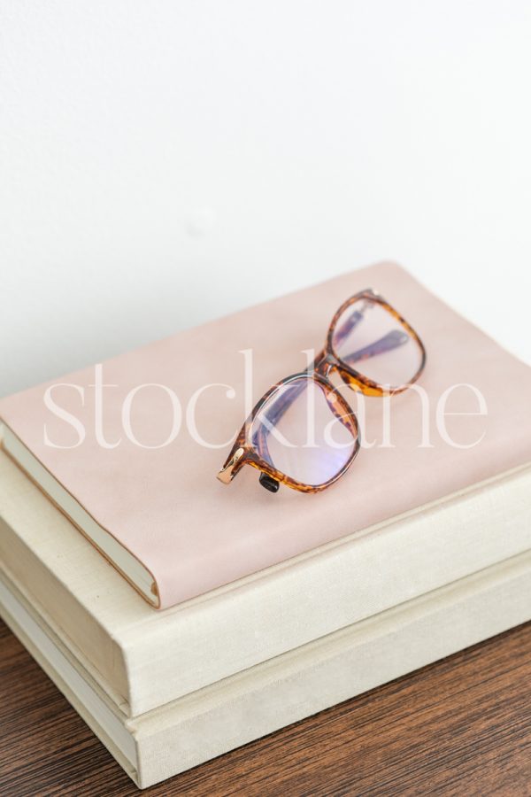 Vertical stock photo of glasses on a stack of books.