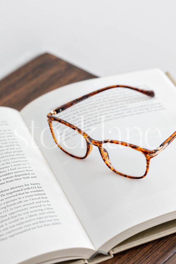 Vertical stock photo of a book and glasses on a table