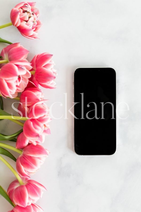 Vertical stock photo of pink tulips and a phone.