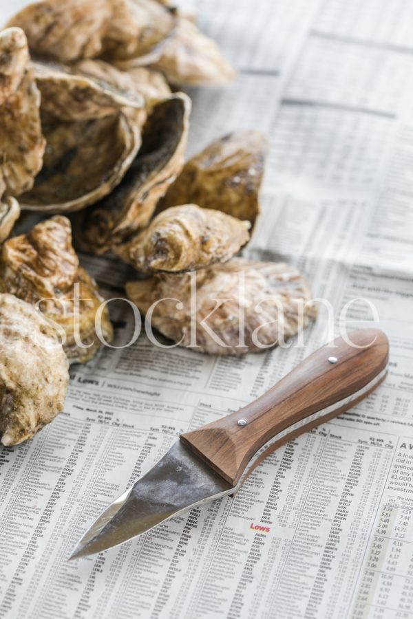 Vertical stock photo of oysters and an oyster-shucking knife.