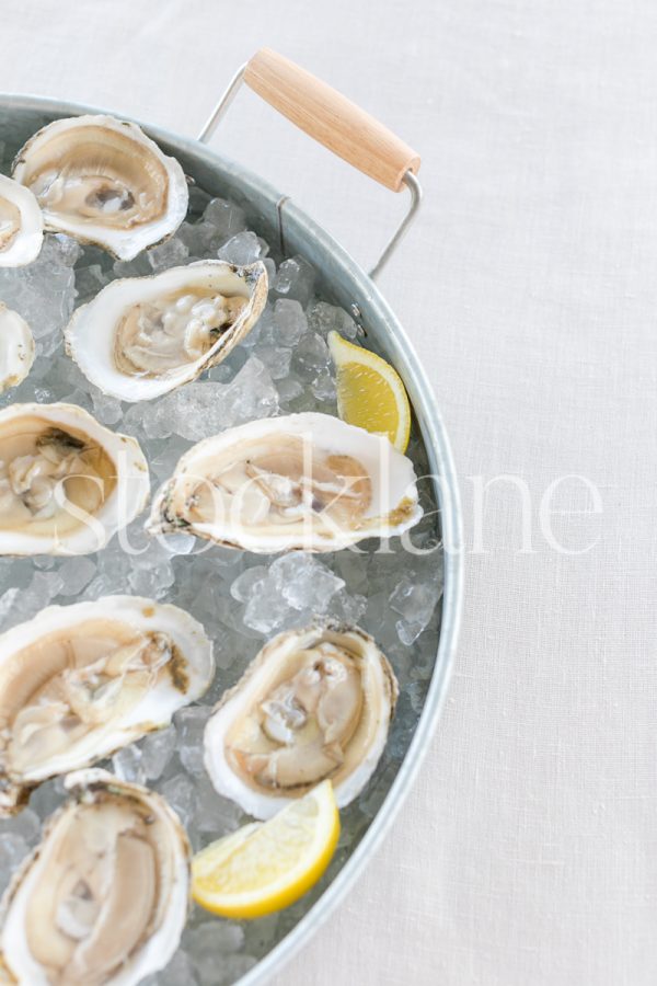 Vertical stock photo of a tray with oysters on ice.