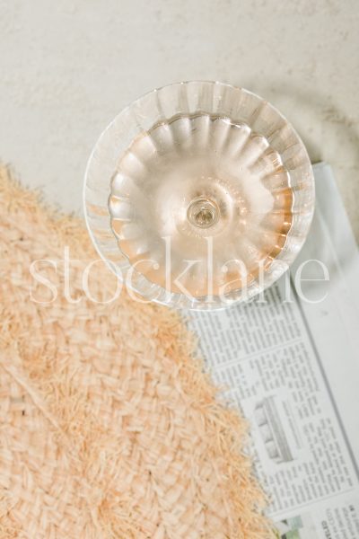 Vertical stock photo of a glass of Rose wine and a hat.