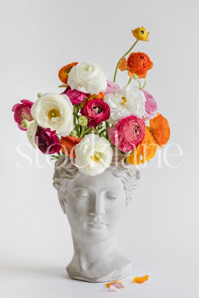 Vertical stock photo of a sculpture toped with colorful flowers.